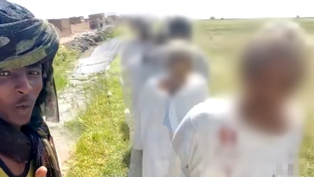 Les captifs passent devant un garde qui les filme. Beaucoup semblent âgés et certains portent des robes blanches.