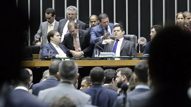 Ao centro, Rodrigo Maia e Davi Alcolumbre aparecem sentadosfantaslot freebetmesa no Plenário da Câmara, rodeados por parlamentares e assessores que falam com eles