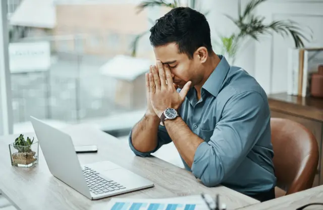 Homem com a mão no rosto preocupadobr4bet paga mesmofrente a laptop