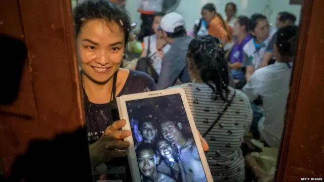 Relatives of the missing boys show photos of them after the 12 boys and their soccer coach have been found alive in the cave where they've been missing for over a week after monsoon rains blocked the main entrance on July 02, 2018 in Chiang Rai