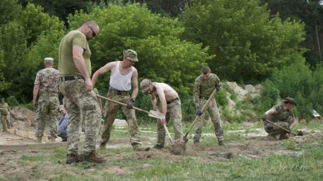 Мужчины в военной форме копают окопы