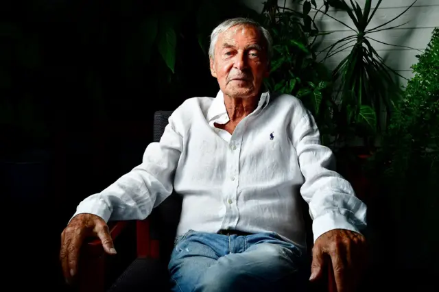 Erno Rubik posando para foto, sentadojogos para ganhar dinheiro no picpaycadeira, com sorriso tímido