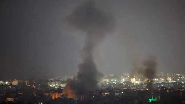夜の市街地の複数個所から黒煙が上っている