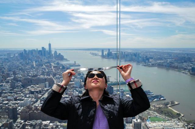 Mujer con lentes especiales para ver el eclipse desde lo alto de un rascacielos en Nueva York.