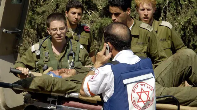 عنصر من الإسعاف الإسرائيلي وعناصر من الجيش الإسرائيلي يحملون جنديا مصابا على حمالة طبية