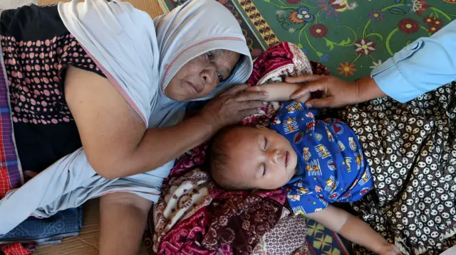 Pengungsi bencana banjir luapan Sungai Tingkeum beristirahat bersama anaknya di posko pengungsian Aceh Masjid Jamie Al-Itiqamah, Ulee Tutue, Bireuen, Aceh, Senin (1/12/2025). Sejumlah pengungsi korban bencana banjir terutama lansia dan balita di Kabupaten Bireuen mulai mengalami gangguan kesehatan deman serta infeksi saluran pernapasan (ispa). 
