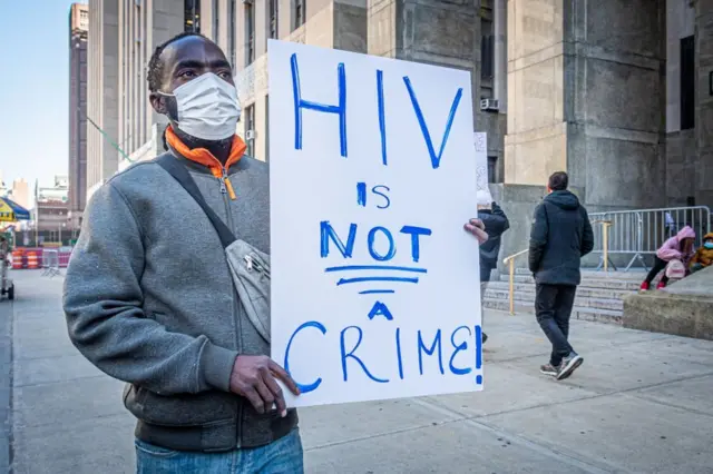 A man holds a banner during a protest organized by the AIDS Coalition To Unleash Power (ACT UP), Housing Works and GMHC outside the New York 1st District Attorney's office on November 9, 2022.