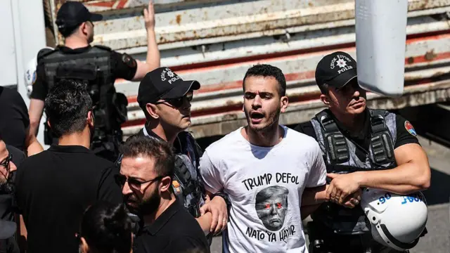 Eylemcilerin bazıları "Trump defol, NATO'ya hayır" yazılı tişörtler giydi