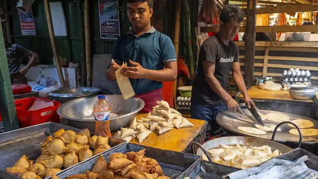 একটি দোকানে দাঁড়িয়ে সমুচা বানাচ্ছেন একজন ব্যক্তি, পাশে কড়াইয়ে তেলে ভাজা হচ্ছে সমুচা। সামনে কতগুলো সিঙ্গারা ও সমুচা রাখা। পাশে দাঁড়ানো আরেকজন একটি বড় তাওয়ায় পরোটা সেঁকছেন