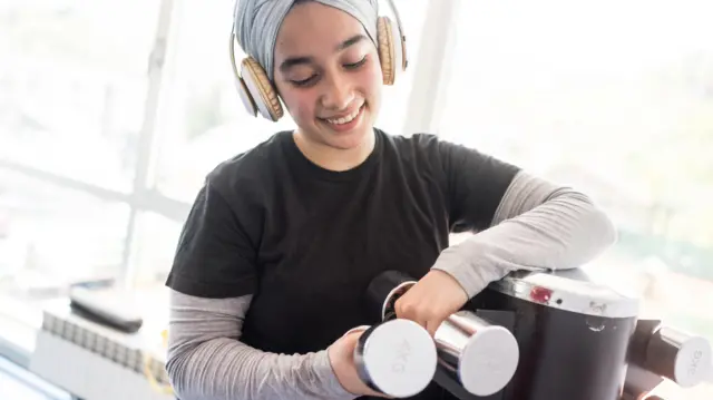 Perempuan memegang dumbbel.