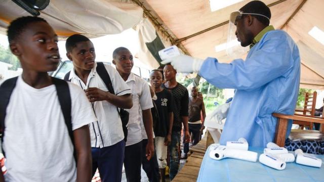 Un agent de santé utilise un thermomètre pour vérifier la température de ressortissants congolais, à la frontière de la RDC avec l'Ouganda, le 12 décembre 2018.