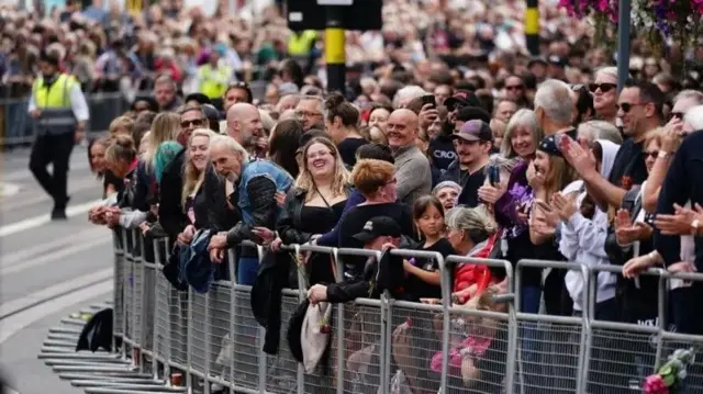 Очень много людей стоит у заграждения