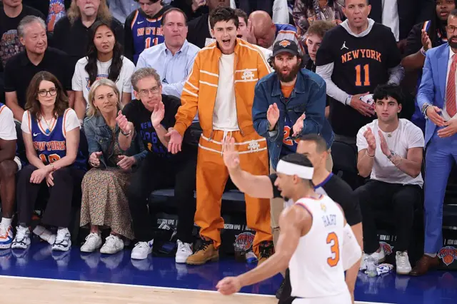 Christine Taylor, Ben Stiller ve Timothée Chalamet saha kenarındaki yerlerinde NBA maçını izliyor.