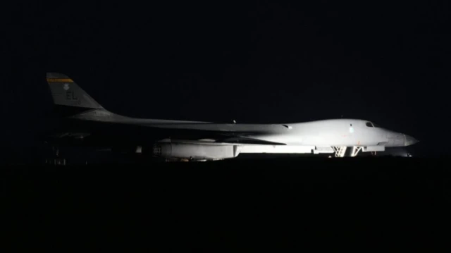 A white bomber plane is pictured flying through the dark night's sky.