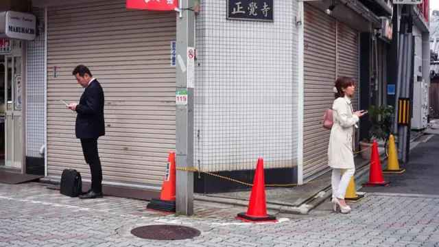 사람들이 핸드폰을 들고 거리에 서있다