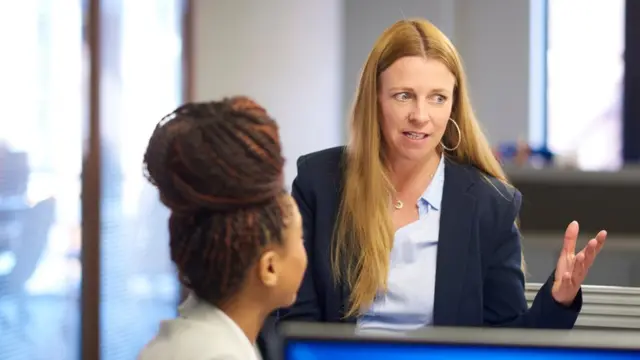 Una mujer hablando con otra en una oficina