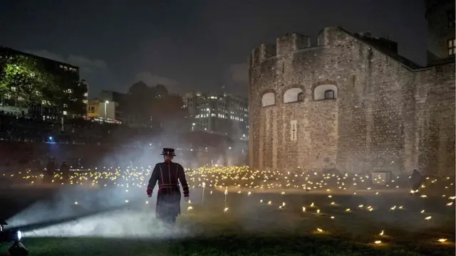 Yeoman Warders, commonly known as "Beefeaters" light the first of thousands of flames in a lighting ceremony in the dry moat of the Tower of London on November 4, 2018