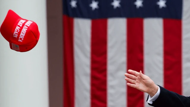 一只手伸出，试图触碰一顶“MAGA”帽