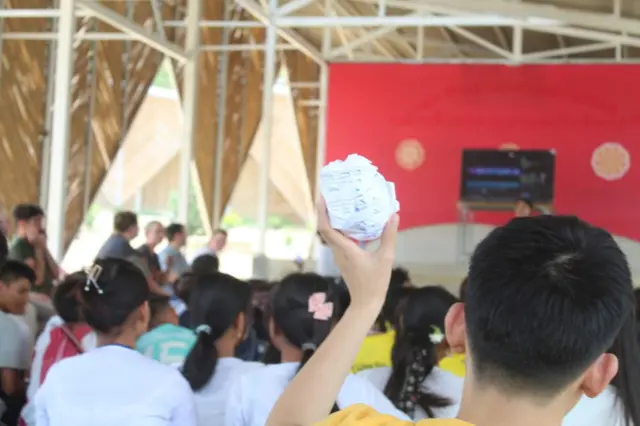 ကျောင်းသားတဦးက စက္ကူလုံးတလုံးကို မြှောက်ပြထားတာက နောက်ကျောက တွေ့ ရတဲ့ မြင်ကွင်း