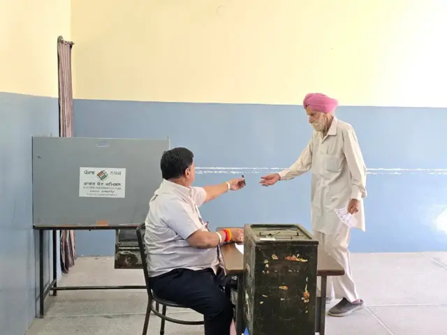 ਇਕ ਪੋਲਿੰਗ ਬੂਥ ਵਿੱਚ ਚੋਣ ਅਮਲੇ ਦਾ ਅਧਿਕਾਰੀ ਅਤੇ ਬਜ਼ੁਰਗ ਵੋਟਰ