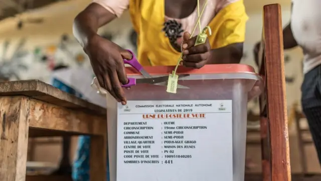 Un membre du personnel électoral coupe le sceau d'une urne dans un bureau de vote lors des élections pour un nouveau parlement à Cotonou le 28 avril 2019.