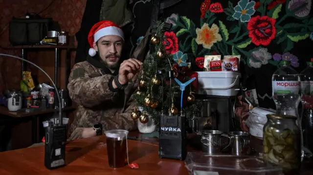 Український військовий у шапці Санти біля ялинки