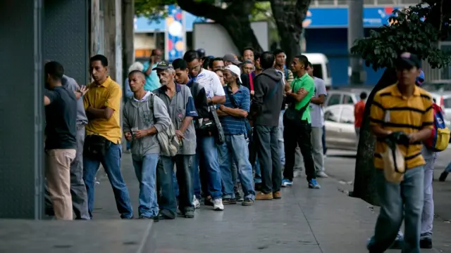 Una cola de personas para entrar en una panadería en Caracas.