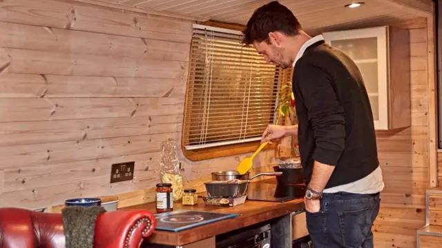 Райан Бэйтман готовит еду на современной кухне, установленной на его лодке