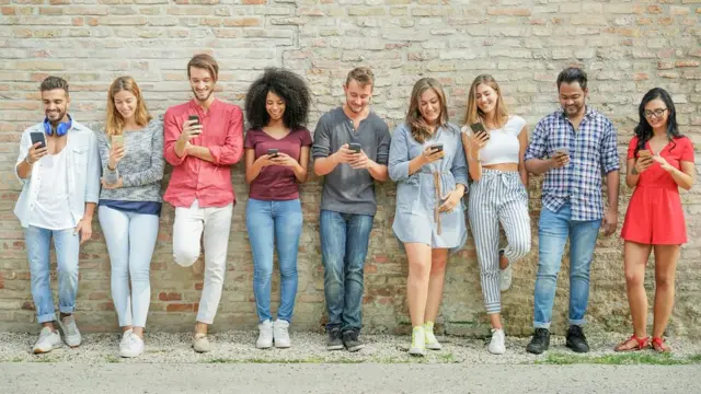 Grupo de millenials mirando sus celulares.