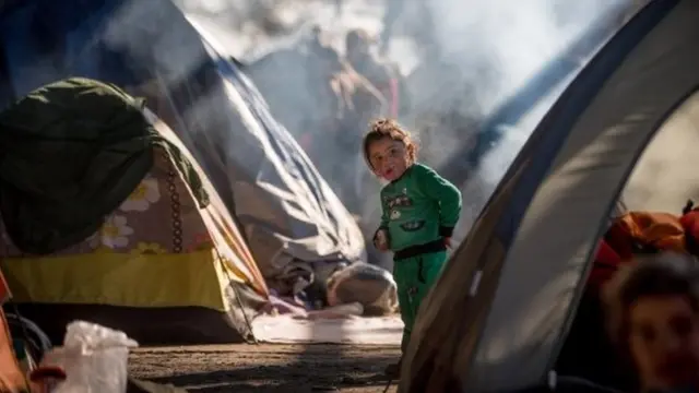 A child wanders between tents erected inside an old railway shed in Idomeni, Greece (23 November 2016)