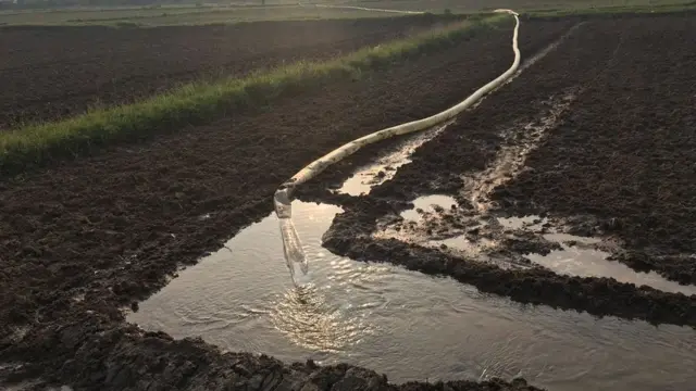 தொலைவிலிருந்து நிலங்களுக்கு பைப் மூலம் விவசாயிகள் தண்ணீர் பாய்ச்சி வருகின்றனர்.