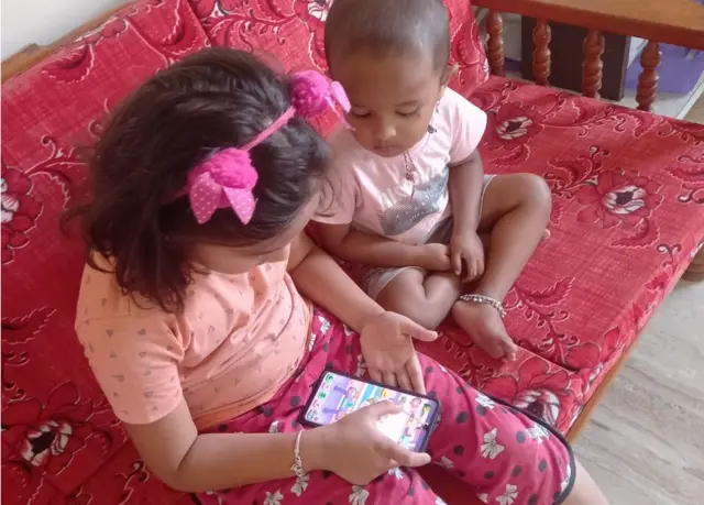 Deux enfants regardant un jeu sur le téléphone.