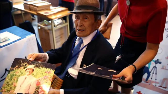 Elderly South Korean man in a wheelchair looking at family photographs
