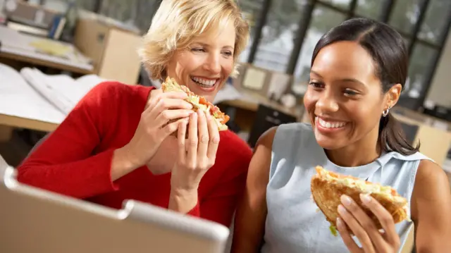 دو زن در حال غذا خوردن و لبخندزنان