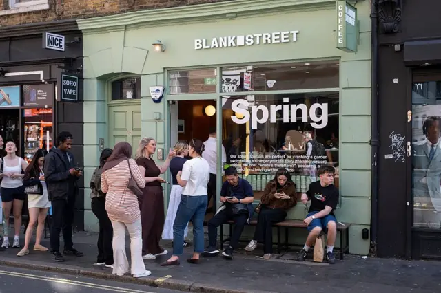 Clientes se sentam do lado de fora de um café Blank Street Coffee no Soho 