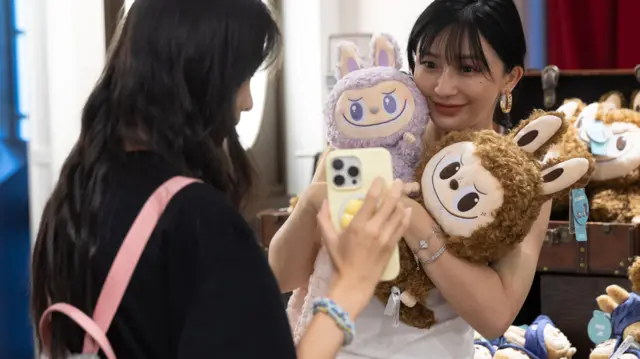 北京某泡泡玛特专卖店内一位女子手抱拉布布玩偶拍照（2/6/2025）