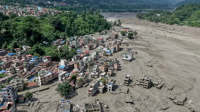 Casas encontram-se parcialmente submersas em águas barrentas à beira de um rio após inundações repentinas em Trishuli Bazar, no distrito de Nuwakot, no Nepal.