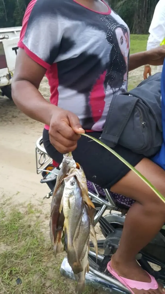 woman sidon for okada wit dead fish wey she pack from waterside