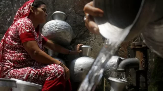 কল থেকে পানি ভরছেন এক নারী