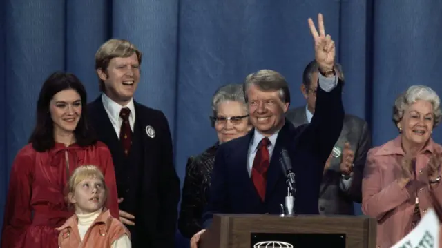 Jimmy Carter bin dey hold up di peace sign and smile wit im family