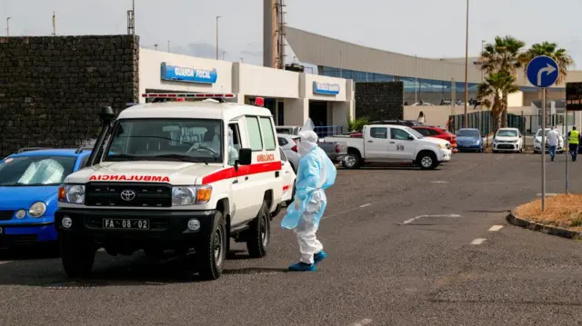 Čovek u zaštitnom odelu pored ambulantnih kola, handavirus