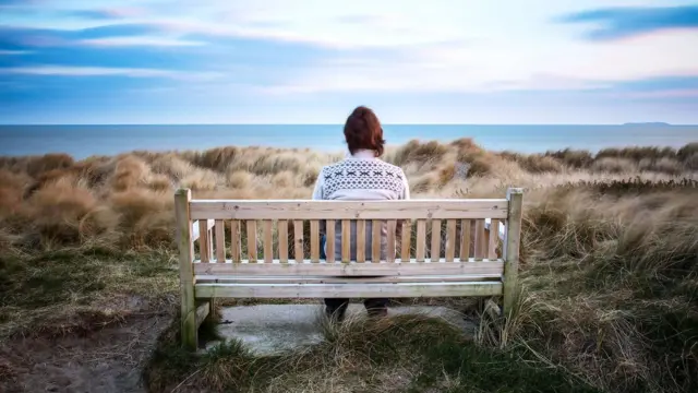 Persona sentada sola frente al mar