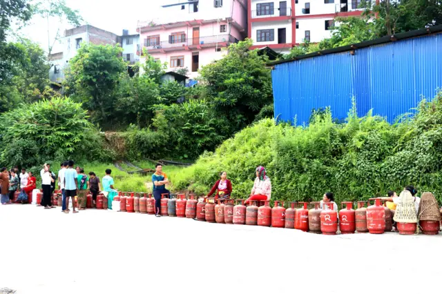 ग्यास पसलमा रित्तो सिलिन्डर लिएर लाम लागेका मानिसहरू