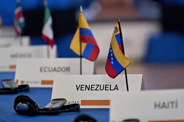 La bandera y un cartel indican el lugar de Venezuela sobre la mesa de una reunión de la OEA