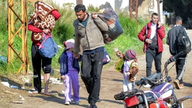 Personas entran al norte del Líbano en plena huida de familias de la minoría alauita siria debido a la violencia sectaria.