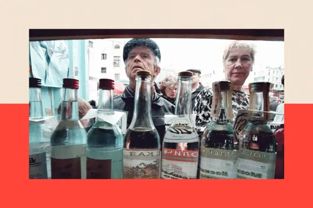 Một người đàn ông và một người phụ nữ đang xem các loại rượu vodka được bày bán trong những chai thủy tinh trong suốt tại một quầy hàng