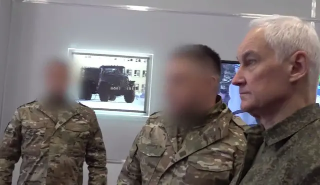 Российский министр обороны Андрей Белоусов и двое военных, изображение лиц которых лишено резкости