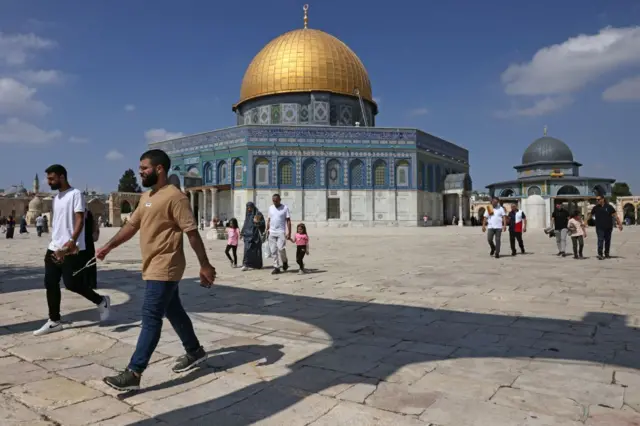 Palestinians walk past the Dome of the Rock at the Al-Aqsa Mosque compound