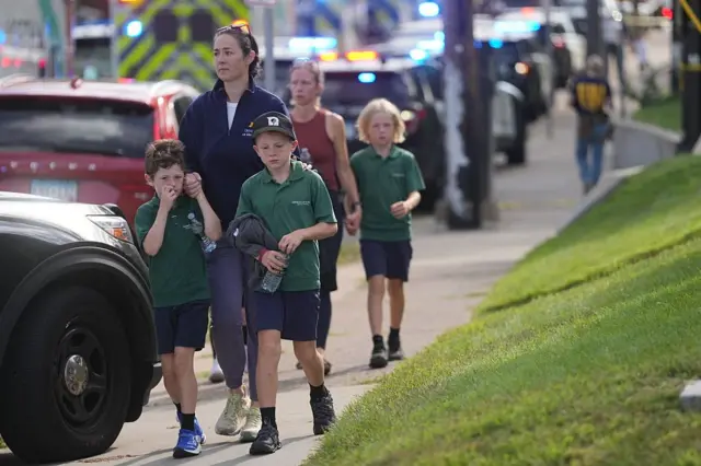 দুই ছেলে শিশুকে নিয়ে হেঁটে সামনের দিকে আসছেন এক নারী, পেছনে আরেকটি ছেলেশিশুর হাত ধরে হেঁটে আসছেন আরেক নারী