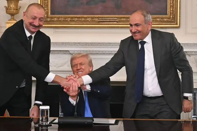 Президент США Дональд Трамп (в центре), президент Азербайджана Ильхам Алиев (слева) и премьер-министр Армении Никол Пашинян пожимают руки после подписания соглашения в Государственной столовой Белого дома в Вашингтоне, округ Колумбия, 8 августа 2025 года